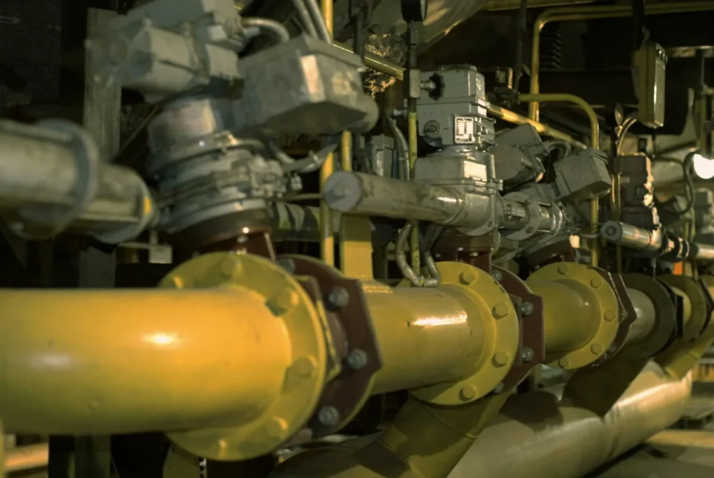 Close-up of industrial pipework and valves with actuators inside a plant.