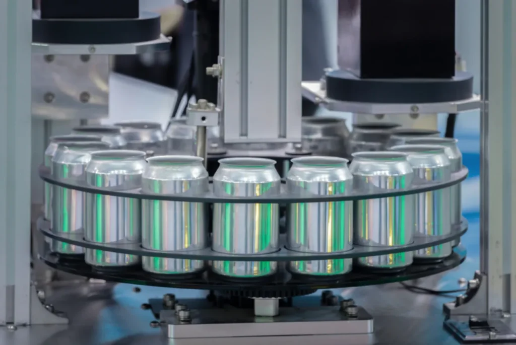 Beverage cans moving through a rotary filling machine on a production line.