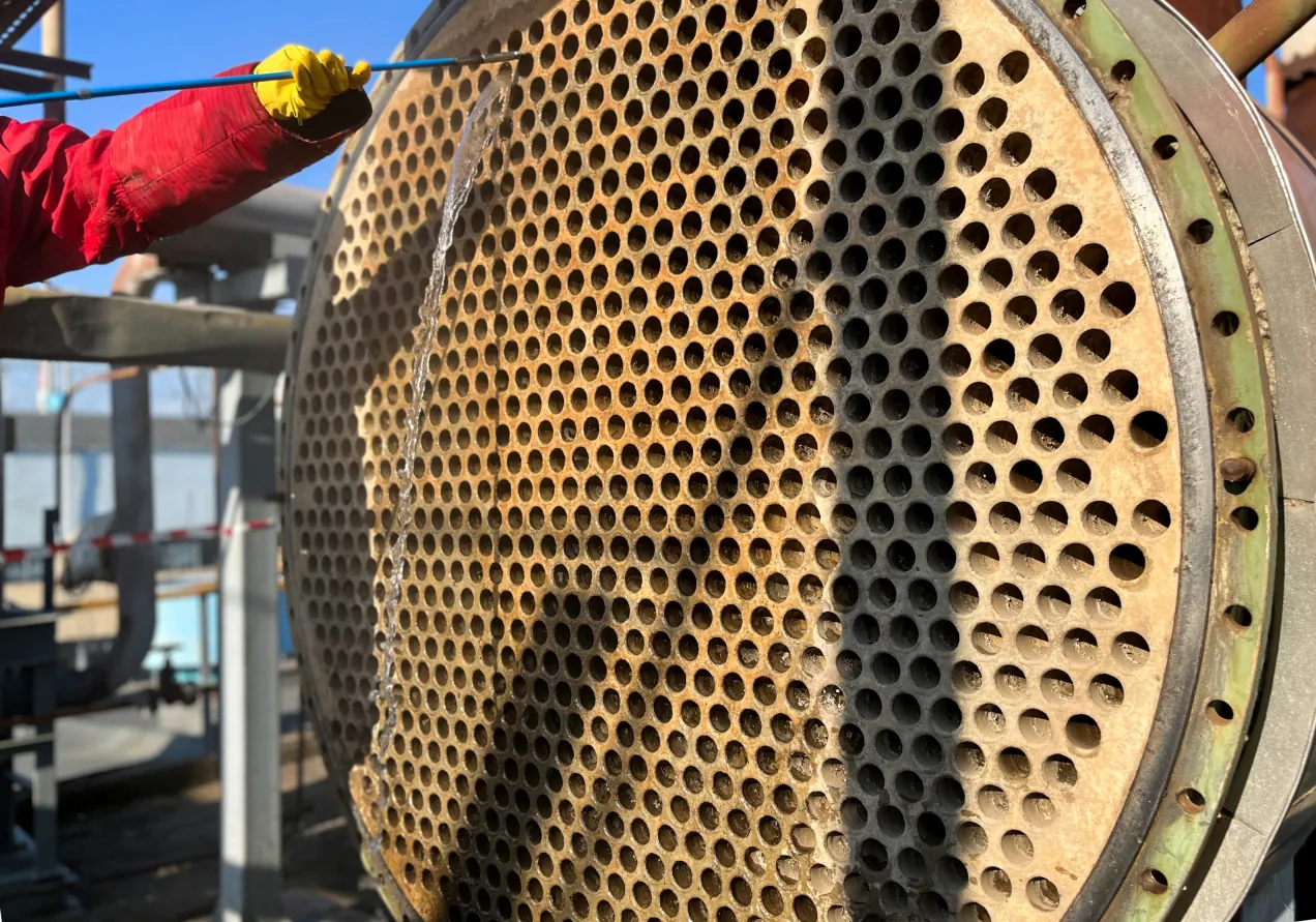The hidden cost of fouling: how a fraction of a millimeter of deposit quietly eats energy, throughput, and margin Technician cleaning the tube sheet of an industrial heat exchanger with a water jet.