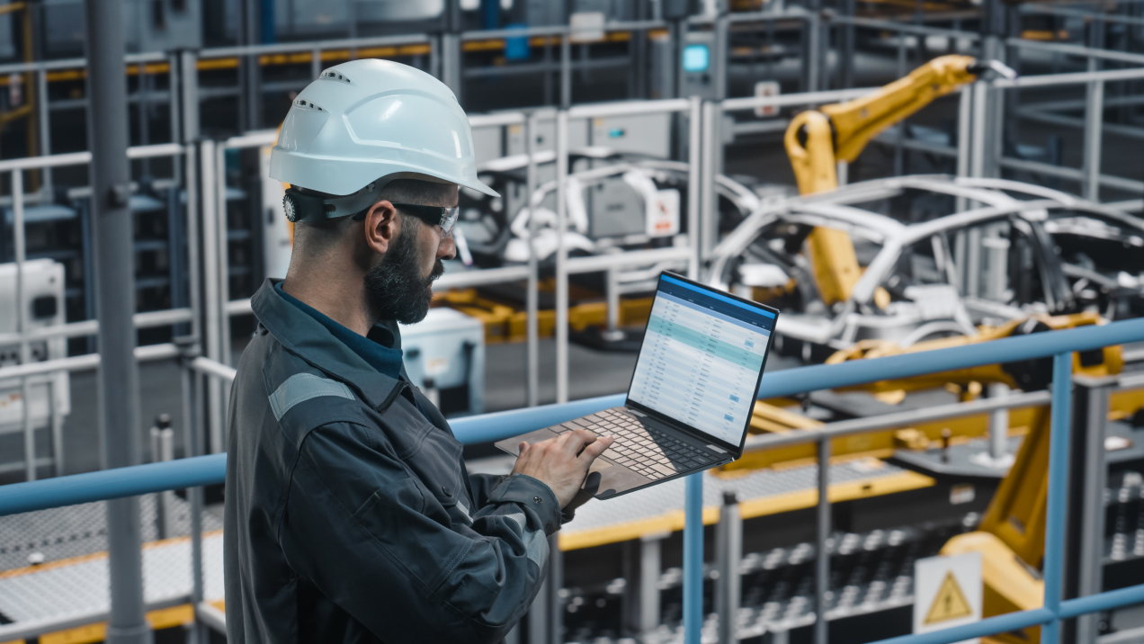 Engineer using laptop in car factory