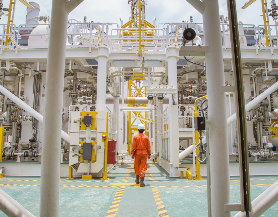 Technician walking through offshore oil and gas process plant